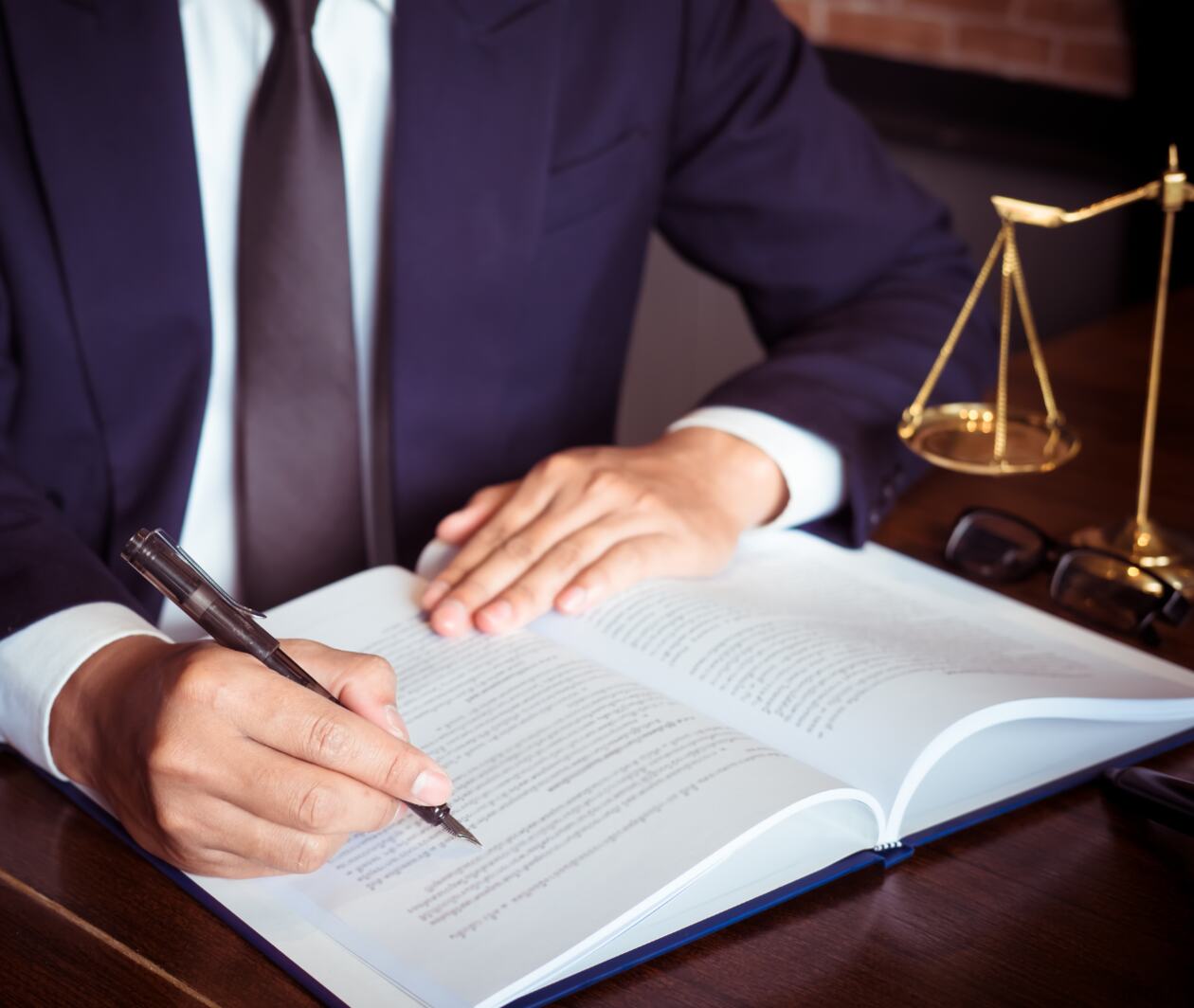 A man reading a book with a pen in hand ready to make notes.