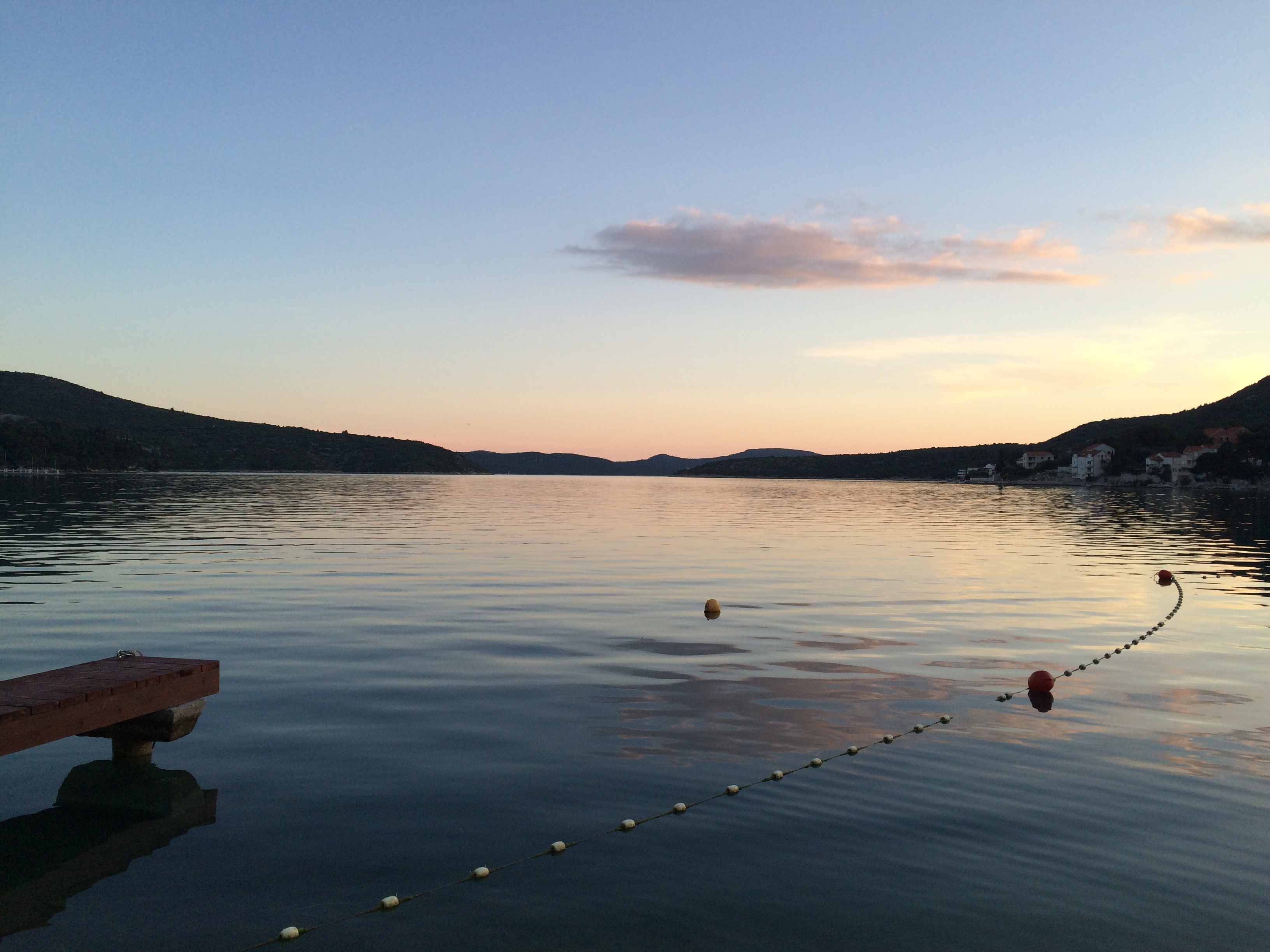 Photograph of dusk over a bay with calm waters, surrounded by mountains