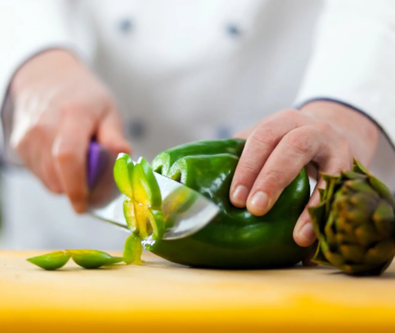 Chef with a chefs knife slicing a pepper