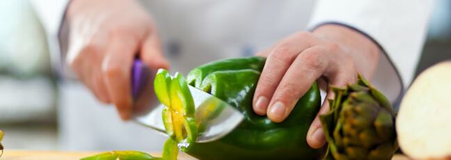 Chef with a chefs knife slicing a pepper