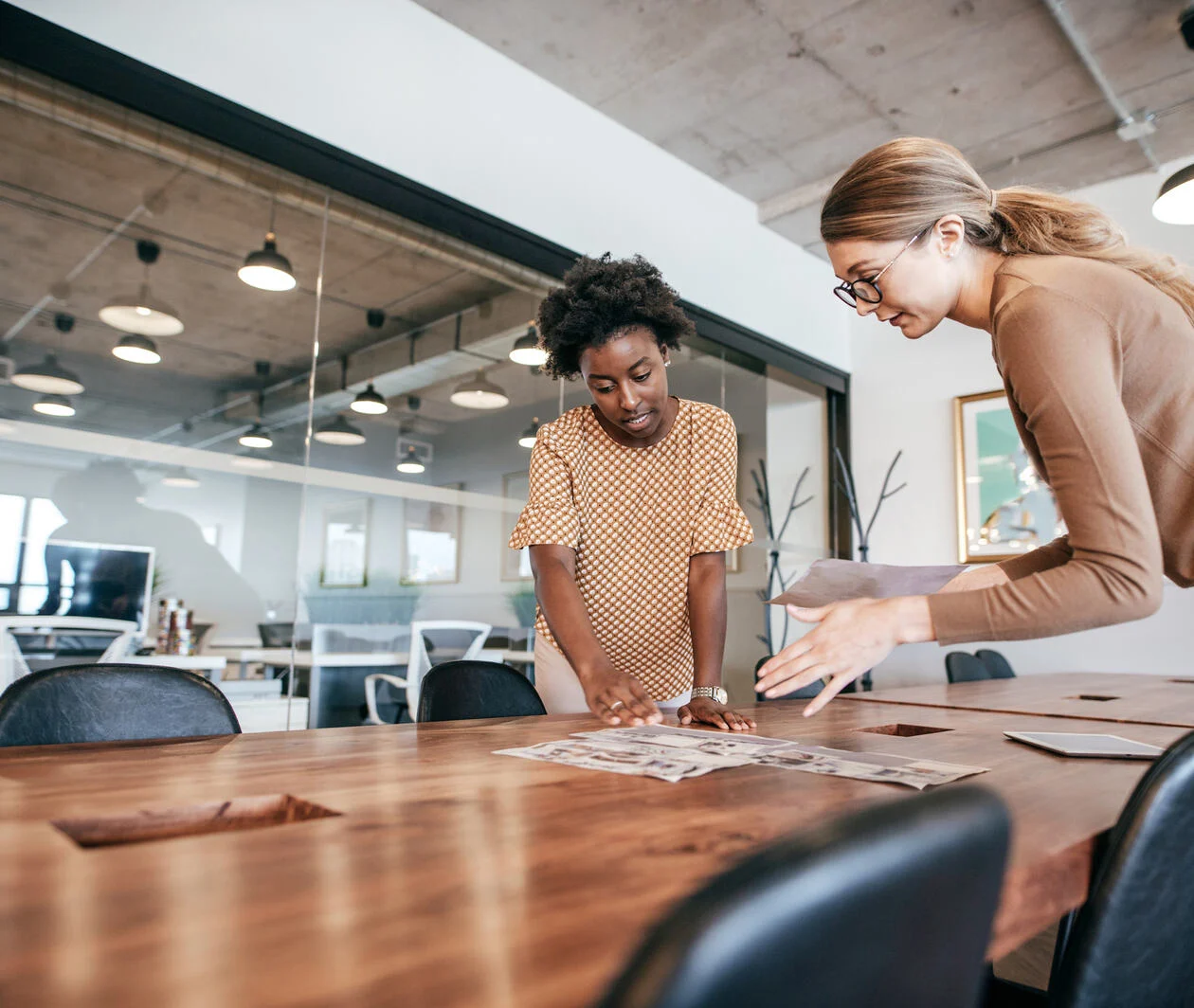 Two women in an office looking over a table discussing behaviour change