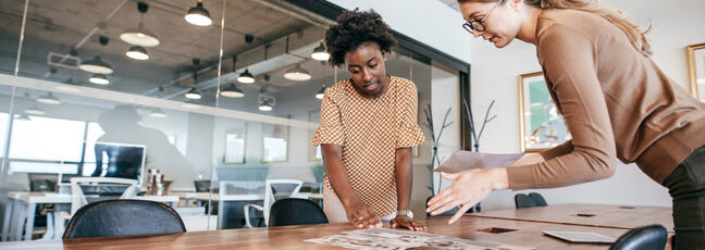 Two women in an office looking over a table discussing behaviour change