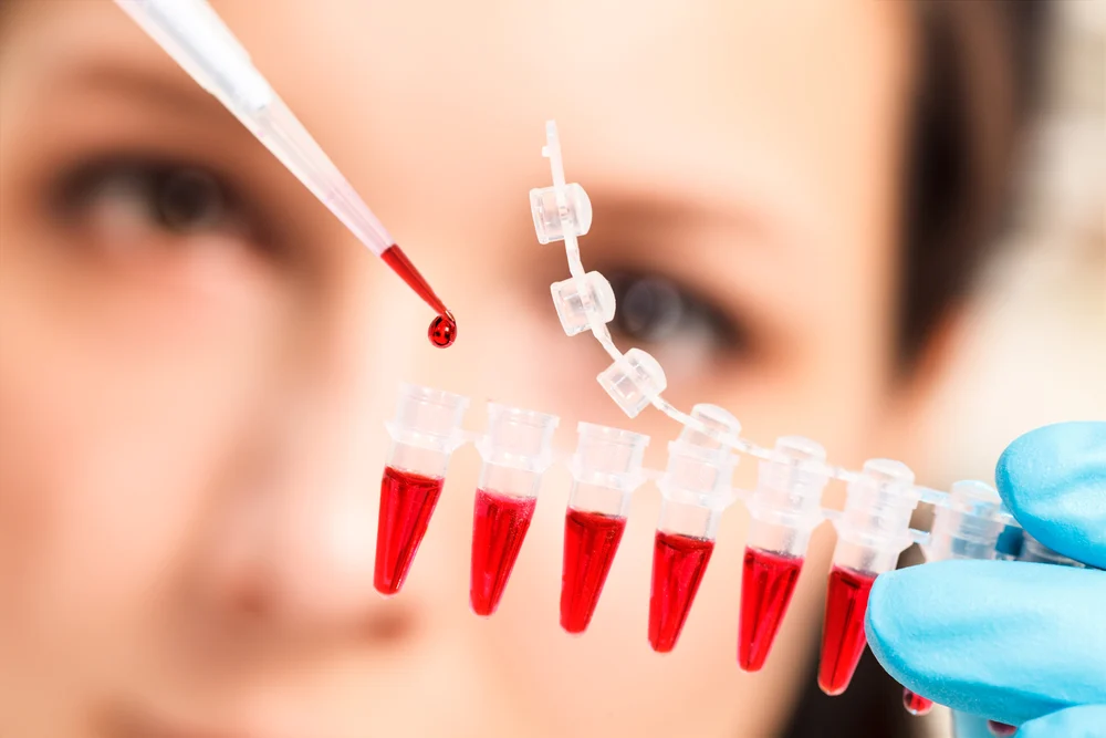 A scientist holding samples of blood in tubes