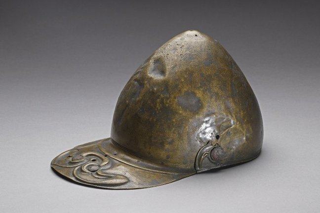 A peaked helmet from the Iron age, fabricateed from beaten copper, it has a slightly pointed crown and a metal peak.
