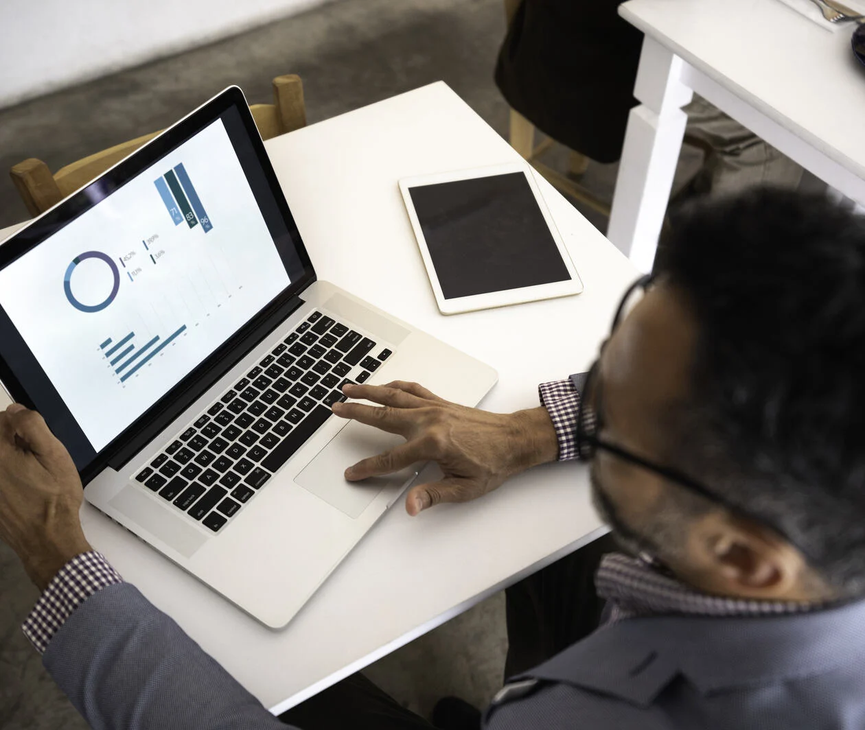 a man looking at his laptop screen which shows microsoft excel